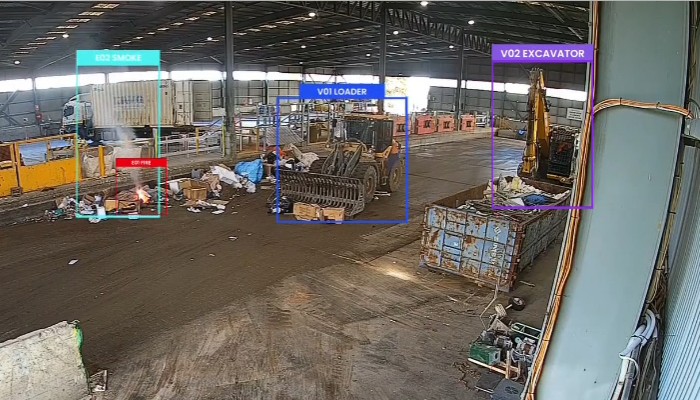 A waste-site camera feed in the VisionCTRL Live View with smoke and a small fire outlined and labelled, and a loader and an excavator also detected